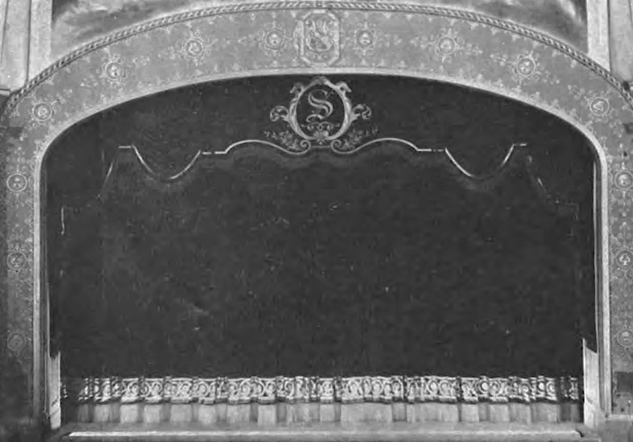 The stage of the Strand Theatre in Brooklyn in 1919, with a painted arch above and a heavy velvet curtain drawn across the opening.