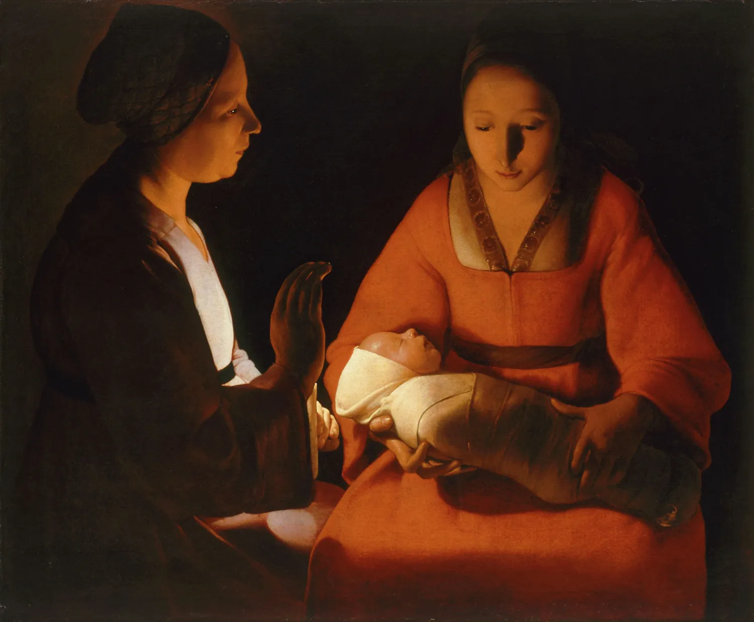 A young mother in red holds a swaddled newborn. A woman beside her shields a candle with her hand, and its light falls on the baby and on both faces. The rest of the room is dark.