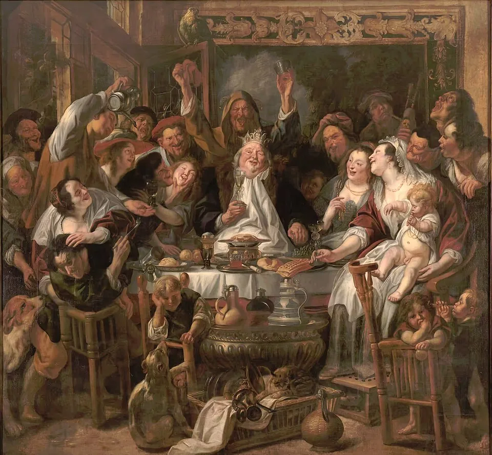 A crowded, noisy Flemish family feast around a table, where a man in a paper crown is lifted up and cheered as the bean king.